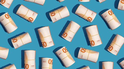 Mehrere Rollen mit 50-Euro-Scheinen liegen auf einem hellblauen Untergrund
