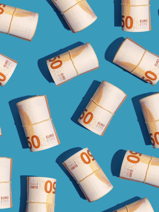 Mehrere Rollen mit 50-Euro-Scheinen liegen auf einem hellblauen Untergrund
