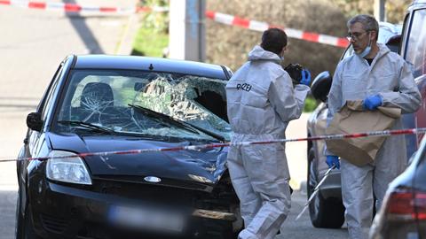 Beamte der Spurensicherung untersuchen ein beschädigtes Fahrzeug an einer Zufahrt zur Rheinbrücke. 