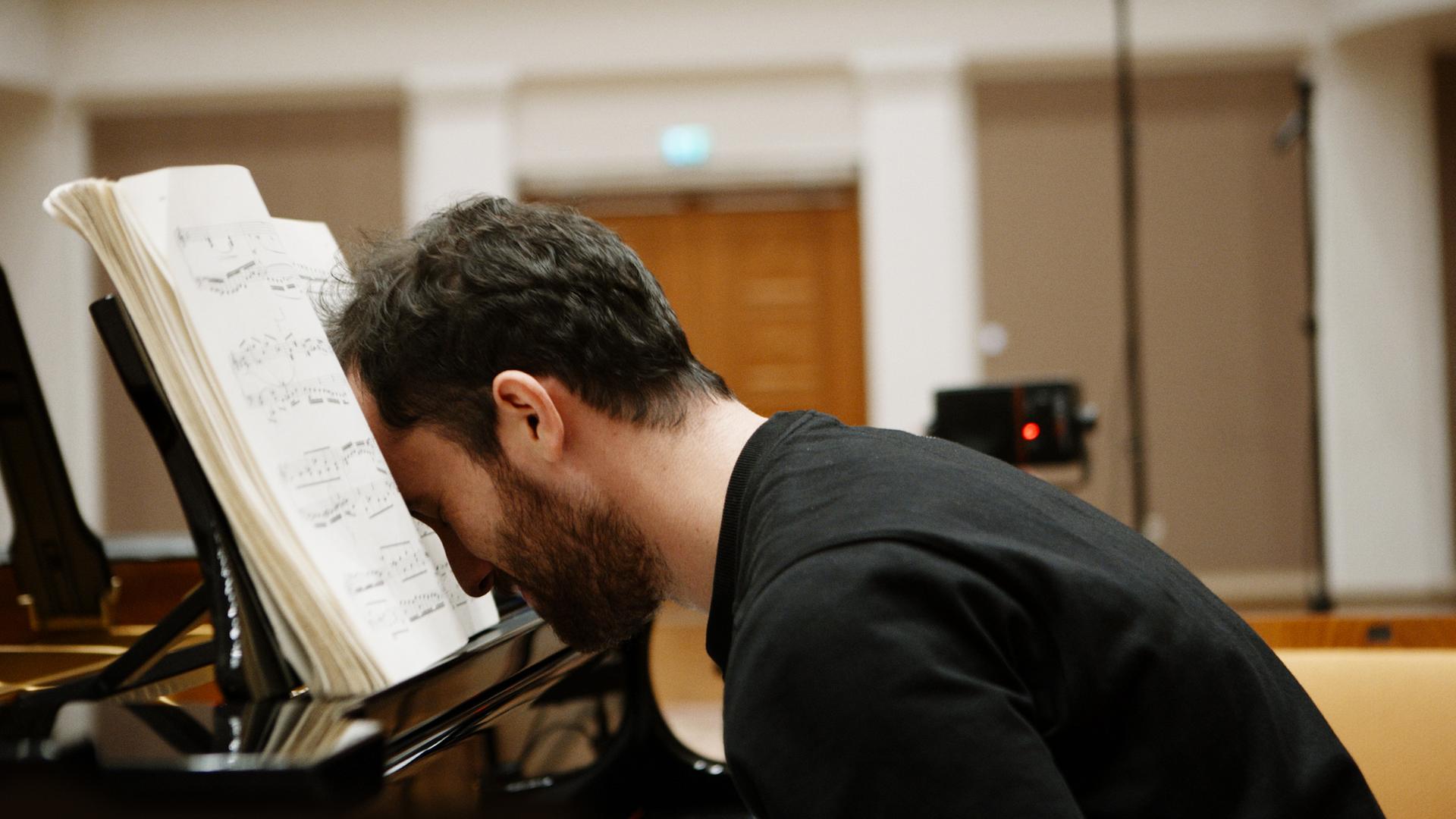 Filmszene aus Igor Levit - No Fear. Levit lehnt mit dem Kopf erschöpft auf den Noten auf seinem Klavier.