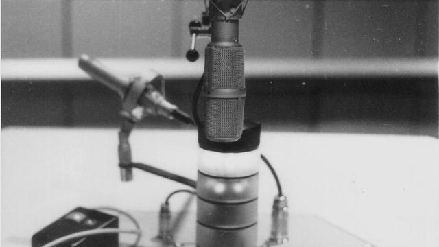 Schwarz-Weiß-Aufnahme zeigt Mikrofon und Kommandofeld eines Sprechertischs beim Deutschlandfunk, 1990