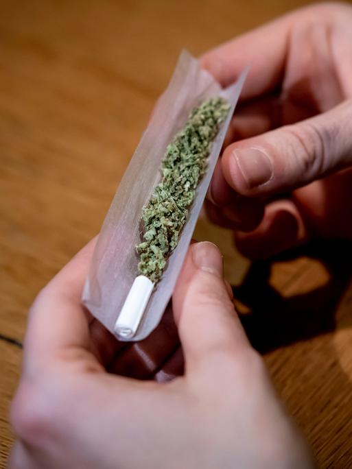 Zwei Hände drehen einen Joint. 