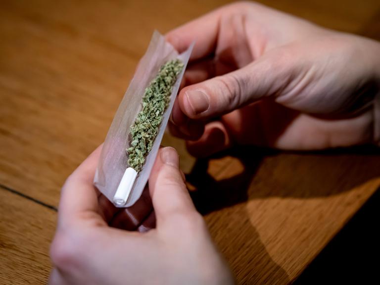 Zwei Hände drehen einen Joint. 