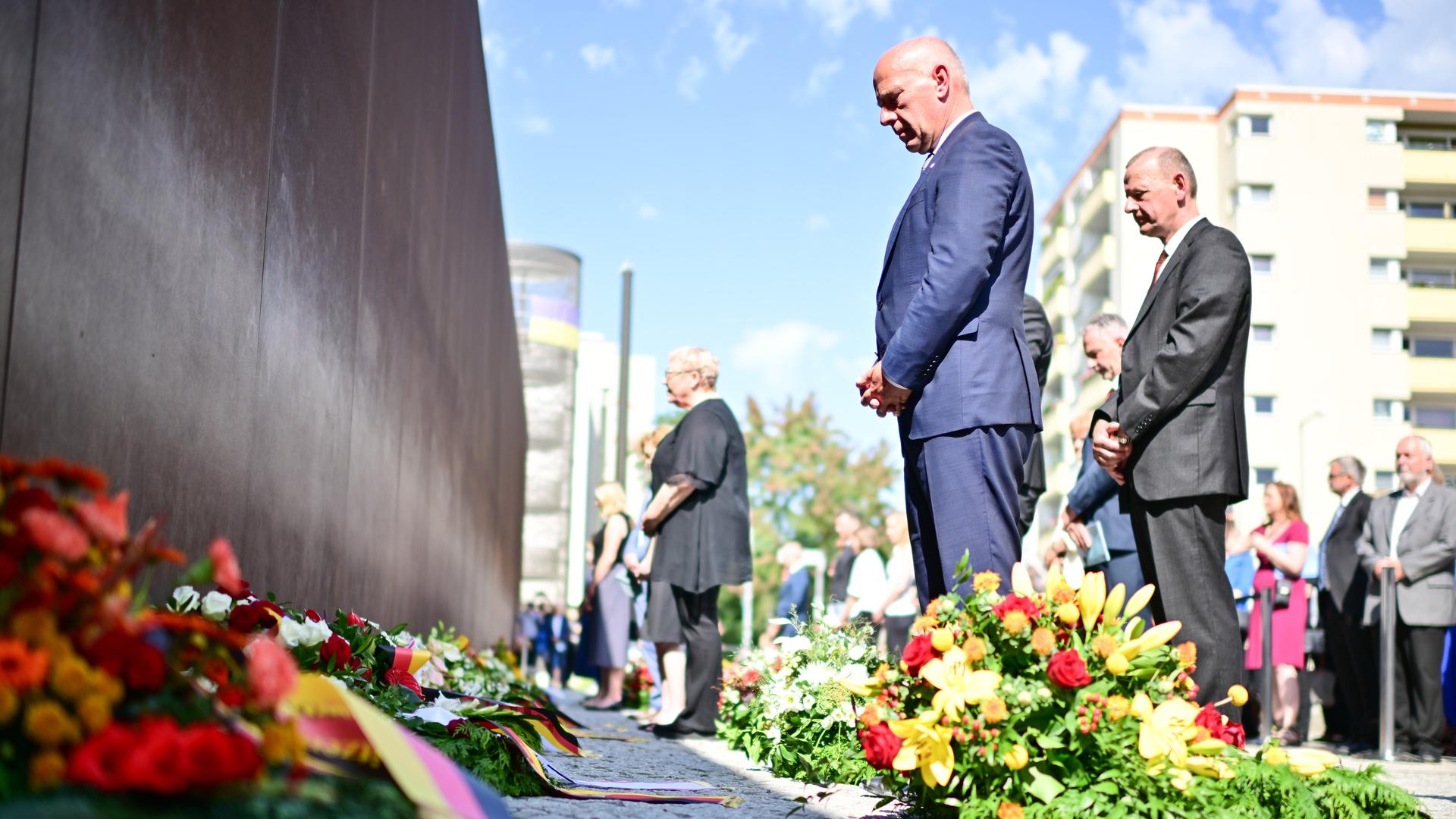 Berlin: Kai Wegner (CDU, M), Regierender Bürgermeister von Berlin, nimmt während einer Kranzniederlegung an der Mauergedenkstätte Ecke Acker-/Bernauer Straße mit weiteren Teilnehmern an einer Gedenkminute teil.