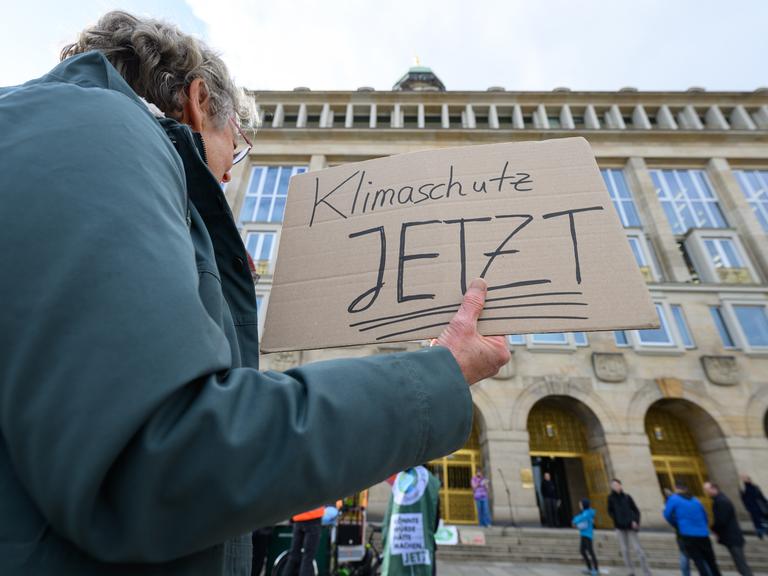 Eine Teilnehmerin eines Bündnisses aus Umweltorganisationen, Wissenschaft und Jugendinitiativen hält bei einer Demonstration in Dresden ein Schild mit der Aufschrift „Klimaschutz jetzt“ in der Hand und fordert u.a. verbindliche Klimaziele.