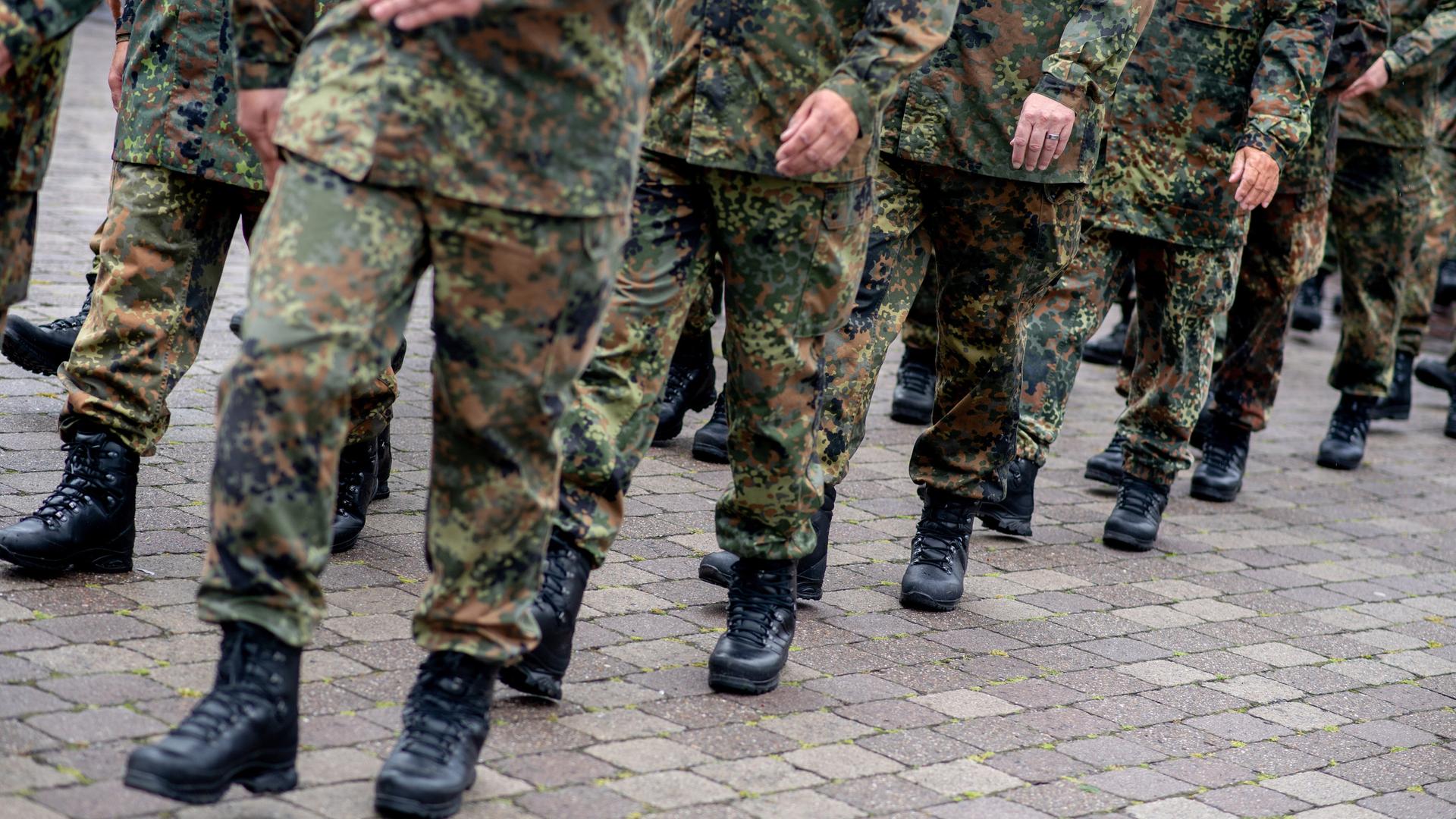 Zu sehen sind die Beine mehrerer Bundeswehr-Soldaten in Tarn-Uniform, die gerade marschieren. Zu sehen sind die Beine mehrerer Bundeswehr-Soldaten in Tarn-Uniform, die gerade marschieren.