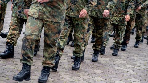 Zu sehen sind die Beine mehrerer Bundeswehr-Soldaten in Tarn-Uniform, die gerade marschieren.