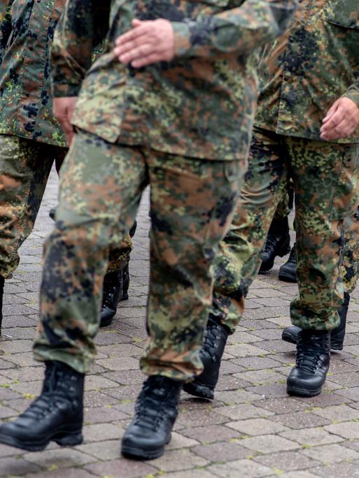 Zu sehen sind die Beine mehrerer Bundeswehr-Soldaten in Tarn-Uniform, die gerade marschieren.