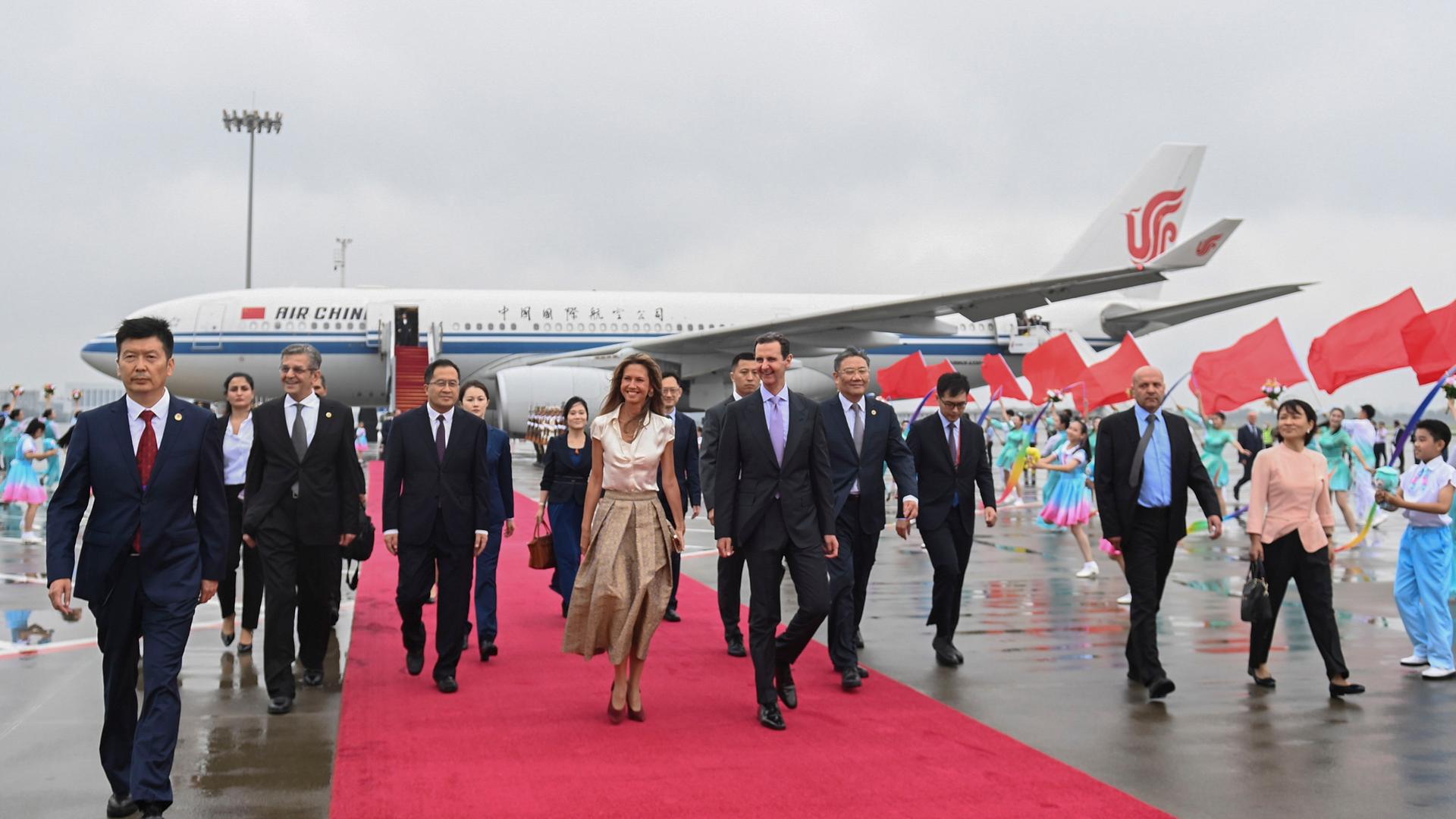 China, Hangzhou: Syriens Präsident Bashar Assad, Mitte rechts, und seine Frau Asma Assad kommen am Flughafen an. Sie werden von mehreren Personen empfangen.