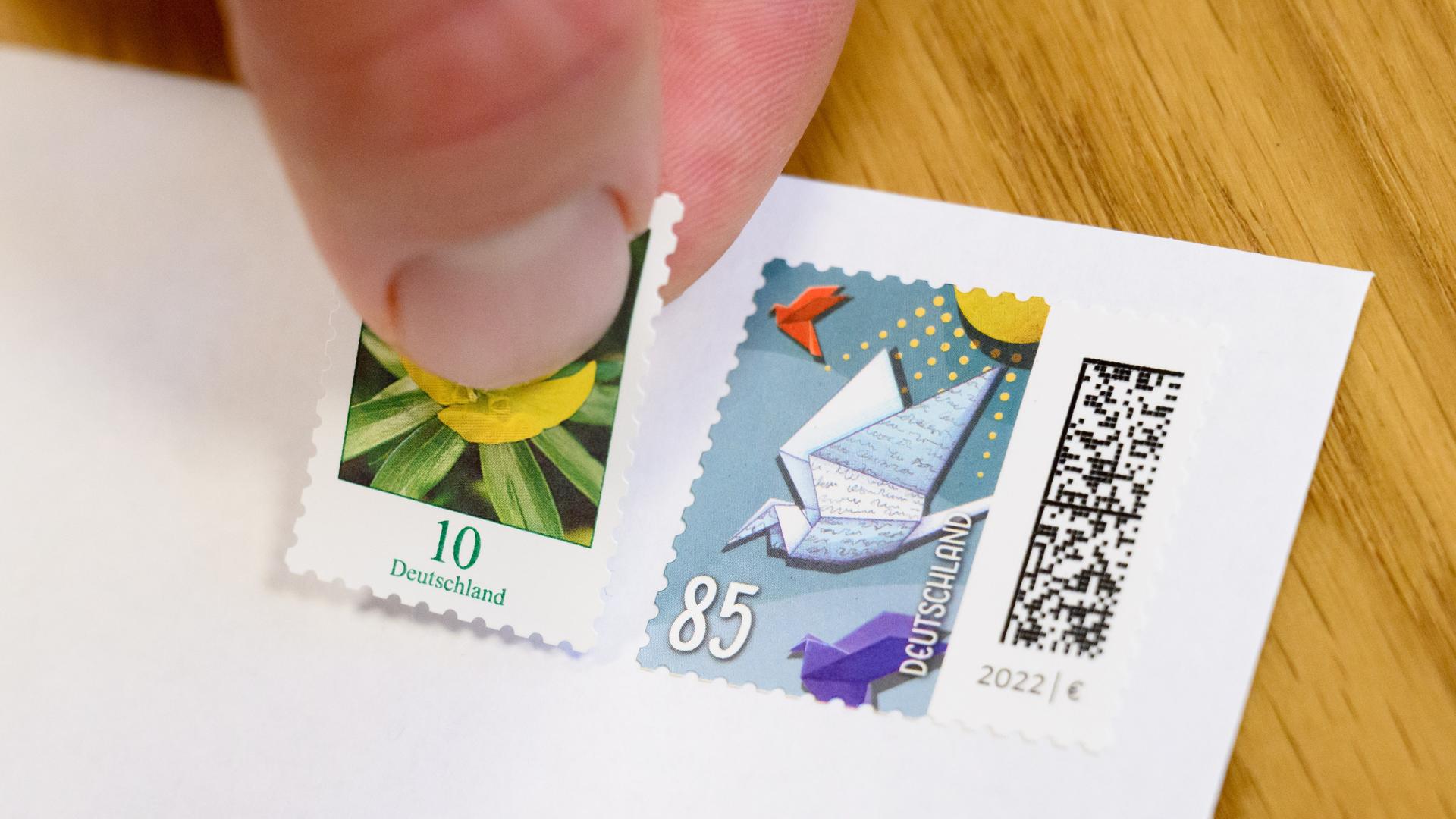 Eine 10-Cent-Briefmarke wird neben eine 85-Cent-Briefmarke geklebt. Eine 10-Cent-Briefmarke wird neben eine 85-Cent-Briefmarke geklebt.