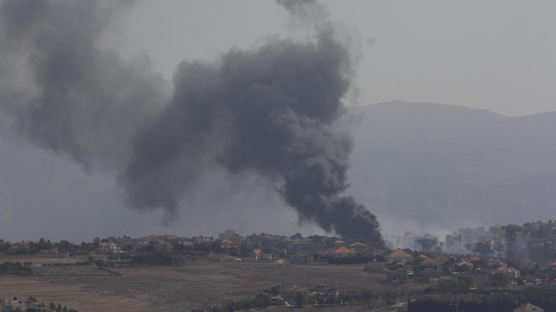 Rauch steigt über Gebäuden in einer leicht hügeligen Landschaft im südlichen Libanon auf 