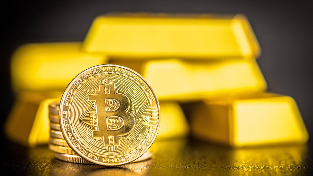 Gold-Bitcoin-Münze und Goldbarren auf schwarzem Tisch. 