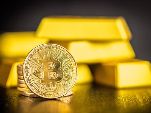 Gold Bitcoin-Münze und Goldbarren auf schwarzem Tisch. 