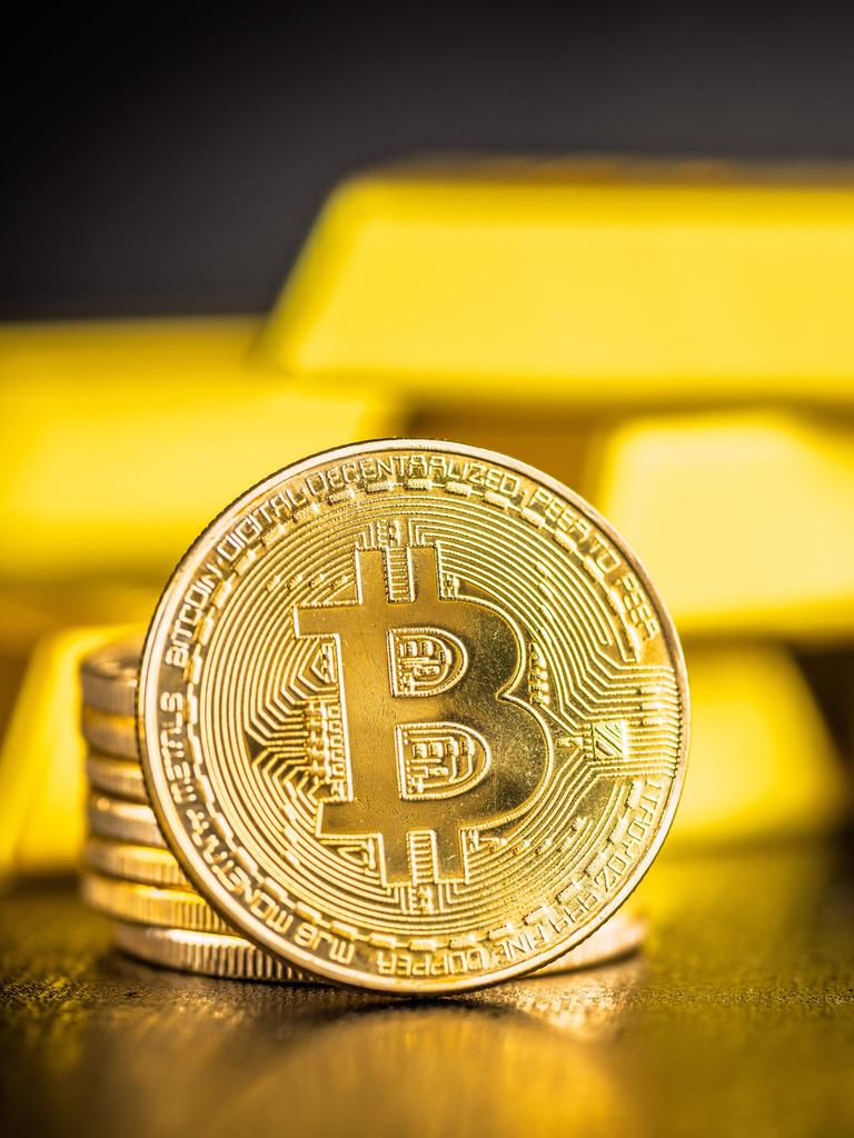 Gold Bitcoin-Münze und Goldbarren auf schwarzem Tisch. 