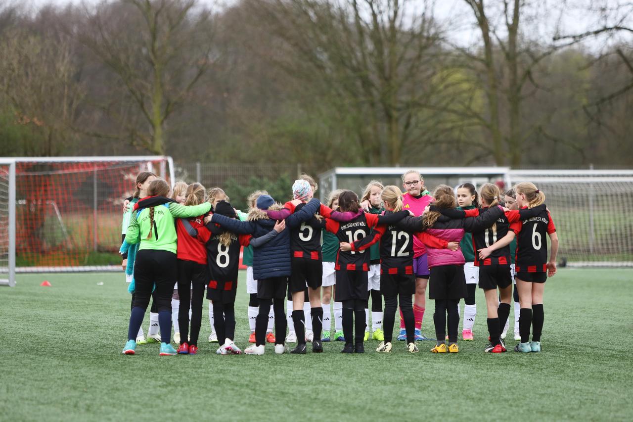 Das Foto zeigt eine Gruppe jugendlicher Fußballerinnen, sie bilden einen Teamkreis und tragen die rot-schwarzen Trikots von DJK Brauweiler.
