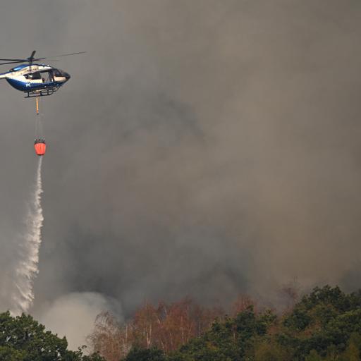 Ein Polizeihubschrauber mit Löschwasser-Außenlastbehälter unterstützt die Löscharbeiten beim Waldbrand im Hürtgenwald.