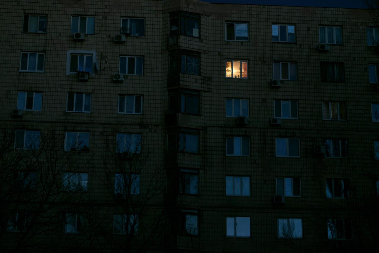 In einem dunklen Mehrfamilienhaus brennt das Licht in einem Zimmer.