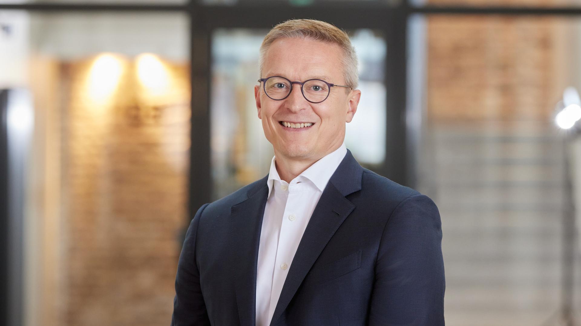 Bundesdigitalminister Karsten Wildberger im dunklen Anzug und weißem Hemd schaut in die Kamera. Bundesdigitalminister Karsten Wildberger im dunklen Anzug und weißem Hemd schaut in die Kamera.