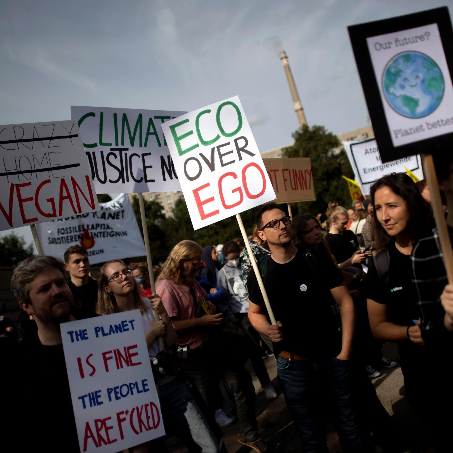 Auf einer Klima-Demonstration hält ein Mann ein kleines Plakat hoch, auf dem steht: Eco statt Ego
