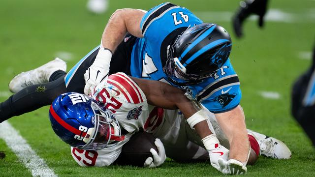 Zwei Football-Spieler kämpfen um den Ball: Tyrone Tracy Jr. von den New York Giants und Josey Jewell von den Carolina Panthers. Tracy liegt unten, Jewell oben. Tracy hält den Ball fest.