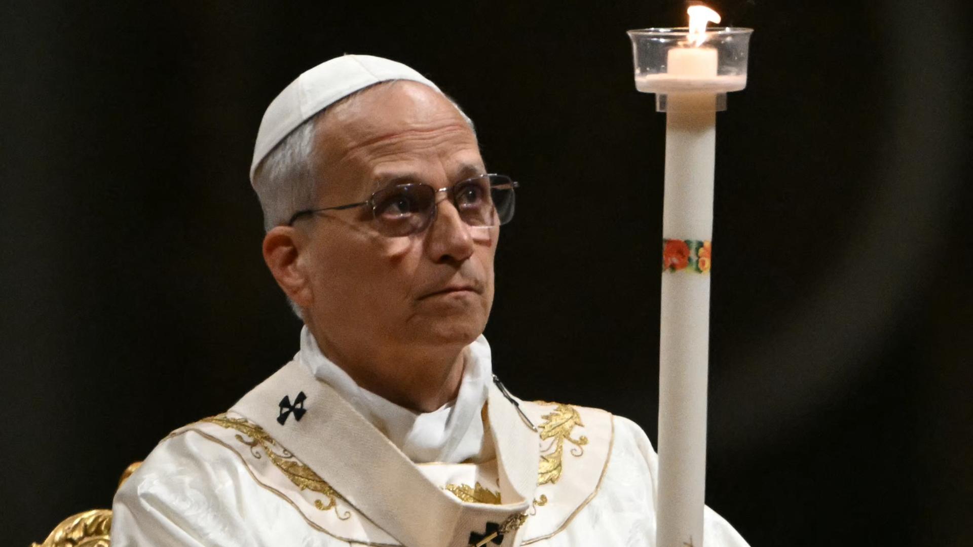 Papst Leo hält eine große Kerze in den Händen und blickt zur Flamme.