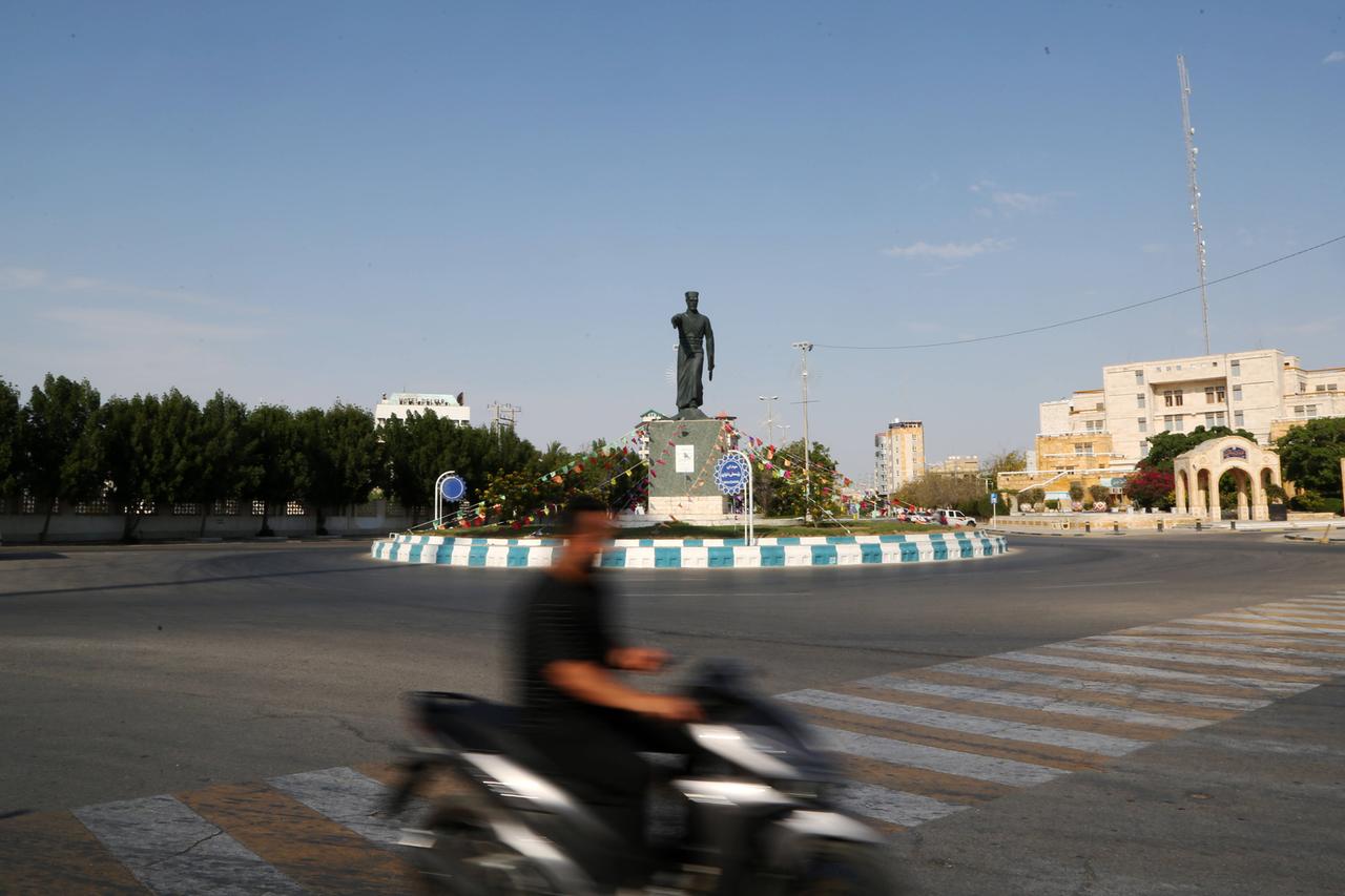 Teilansicht der Stadt Buschehr im Iran. Im Vordergrund ist ein Kreisverkehr, im Hintergrund Gebäude und Bäume. 