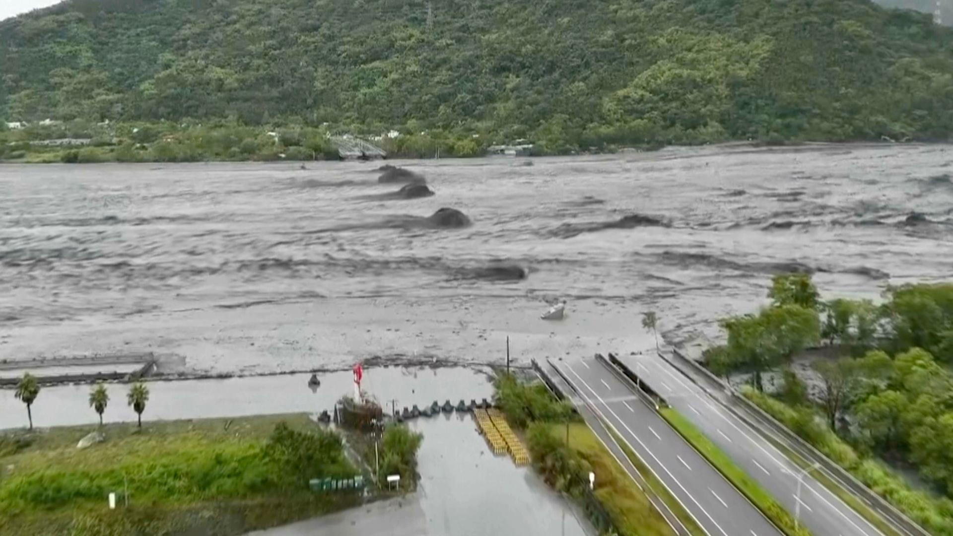 Das Bild zeigt einen reißenden Wasserstrom und eine eingestürzte Brücke, deren Trümmer aus den Fluten ragen.
