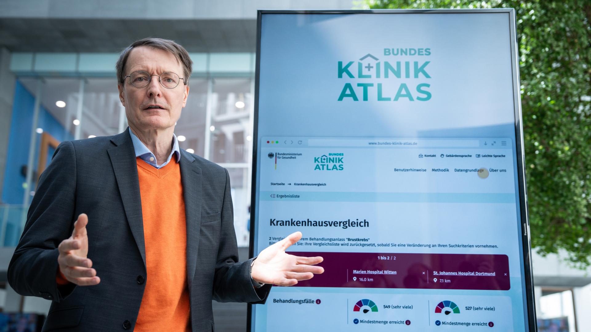 Bundesgesundheitsminister Lauterbach (SPD) steht neben einem Bildschirm, auf dem das neue Klinikatlas-Portal zu sehen ist