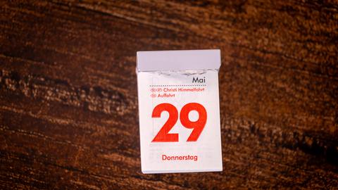 Ein Abreißkalender liegt auf einem Holztisch: Die rote Druckfarbe zeigt, dass der 29. Mai 2025 als Christi Himmelfahrt ein gesetzlicher Feiertag ist.