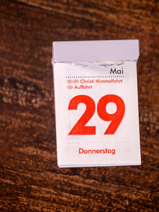 Ein Abreißkalender liegt auf einem Holztisch: Die rote Druckfarbe zeigt, dass der 29. Mai 2025 als Christi Himmelfahrt ein gesetzlicher Feiertag ist.