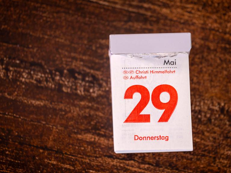 Ein Abreißkalender liegt auf einem Holztisch: Die rote Druckfarbe zeigt, dass der 29. Mai 2025 als Christi Himmelfahrt ein gesetzlicher Feiertag ist.