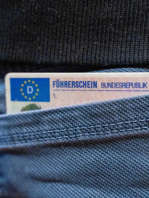 Ein deutscher Führerschein ragt aus einer Hosentasche.