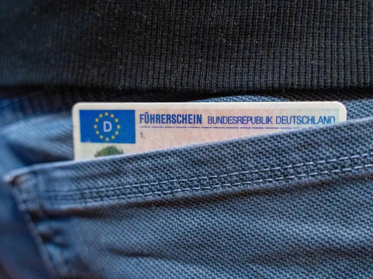 Ein deutscher Führerschein ragt aus einer Hosentasche.