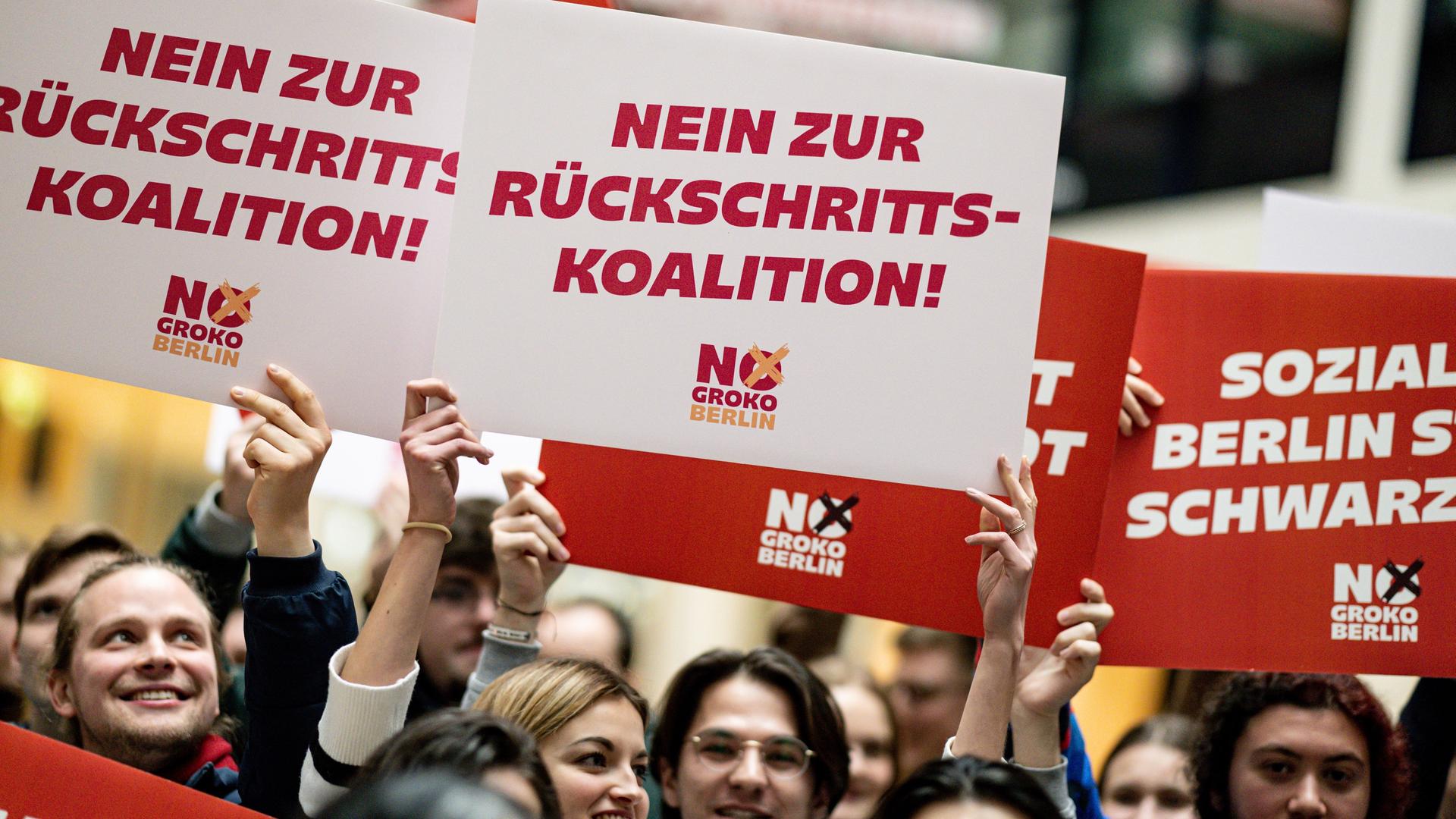 Delegierte halten am Rande der Landesdelegiertenkonferenz der Jusos Berlin im Willy-Brandt Haus Schilder mit der Aufschrift "Soziales Berlin statt Schwarz Rot" und "Nein zur Rückschritts-Koalition" in die Höhe.