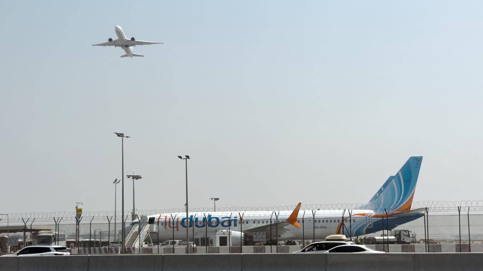 Vereinigte Arabische Emirate, Dubai: Ein Flugzeug hebt ab, während ein Flugzeug der Fluggesellschaft Flydubai auf dem Rollfeld des Dubai International Airport steht. 