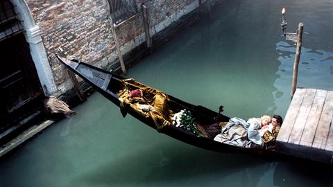 Ein Paar liegt in einer Gondel zusammen in einem einsamen, kleinen Kanal in Venedig.