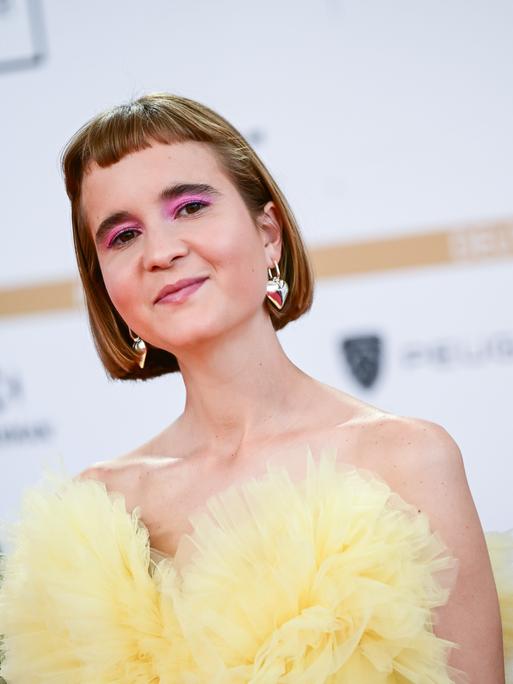 Caroline Wahl, Autorin, bei der Verleihung des Deutschen Filmpreises am Berliner Palais am Funkturm. Sie trägt ein gelbes schulterfreies Kleid. Caroline Wahl, Autorin, bei der Verleihung des Deutschen Filmpreises am Berliner Palais am Funkturm. Sie trägt ein gelbes schulterfreies Kleid.