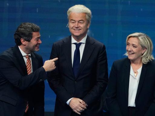 Andre Ventura, Geert Wilders und Marine Le Pen posieren für ein Pressefoto und scherzen miteinander.