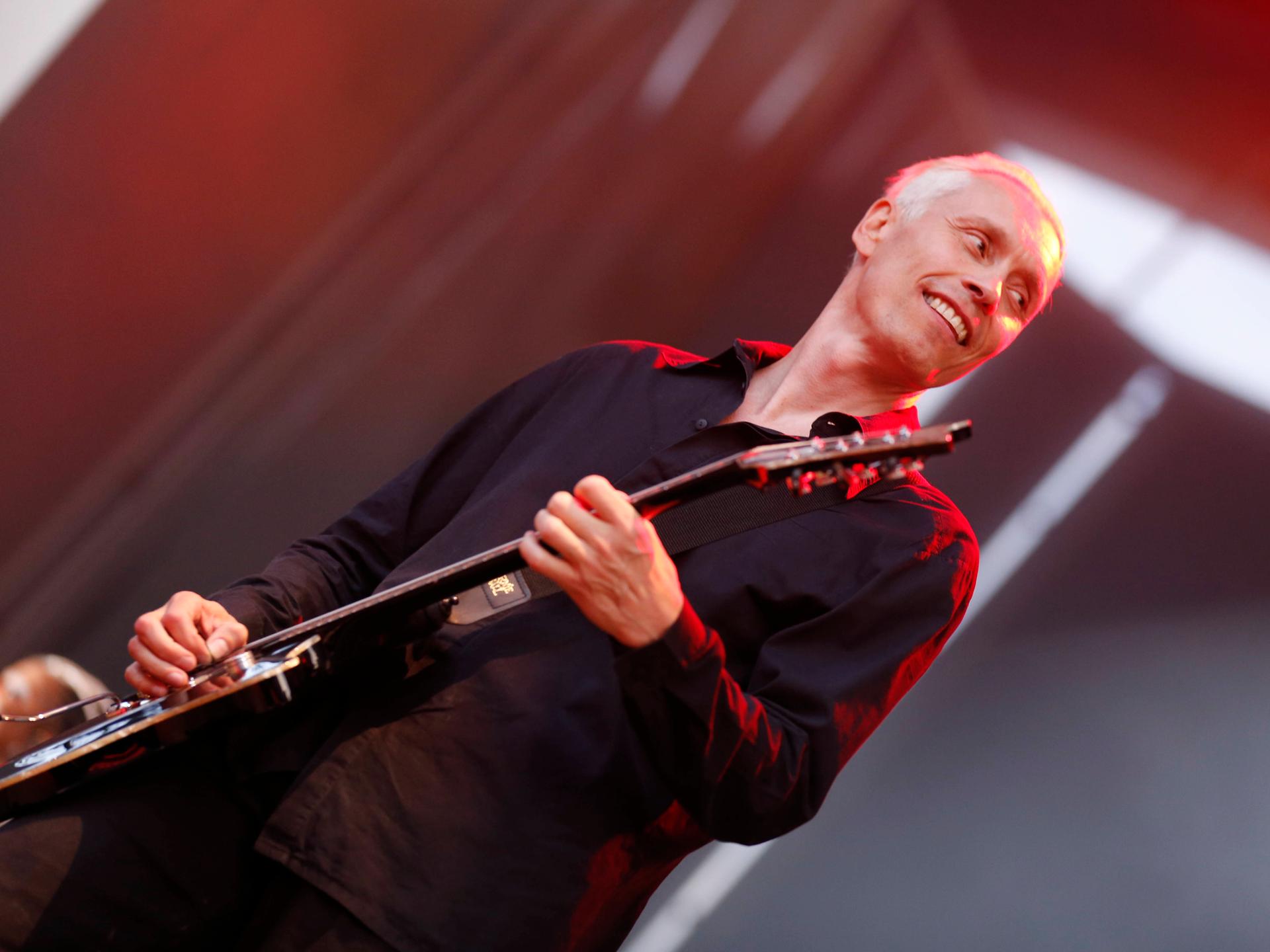 Farin Urlaub spielt auf der Bühne Gitarre und lacht. Farin Urlaub spielt auf der Bühne Gitarre und lacht.