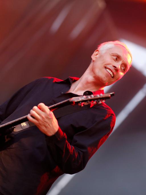 Farin Urlaub spielt auf der Bühne Gitarre und lacht. Farin Urlaub spielt auf der Bühne Gitarre und lacht.