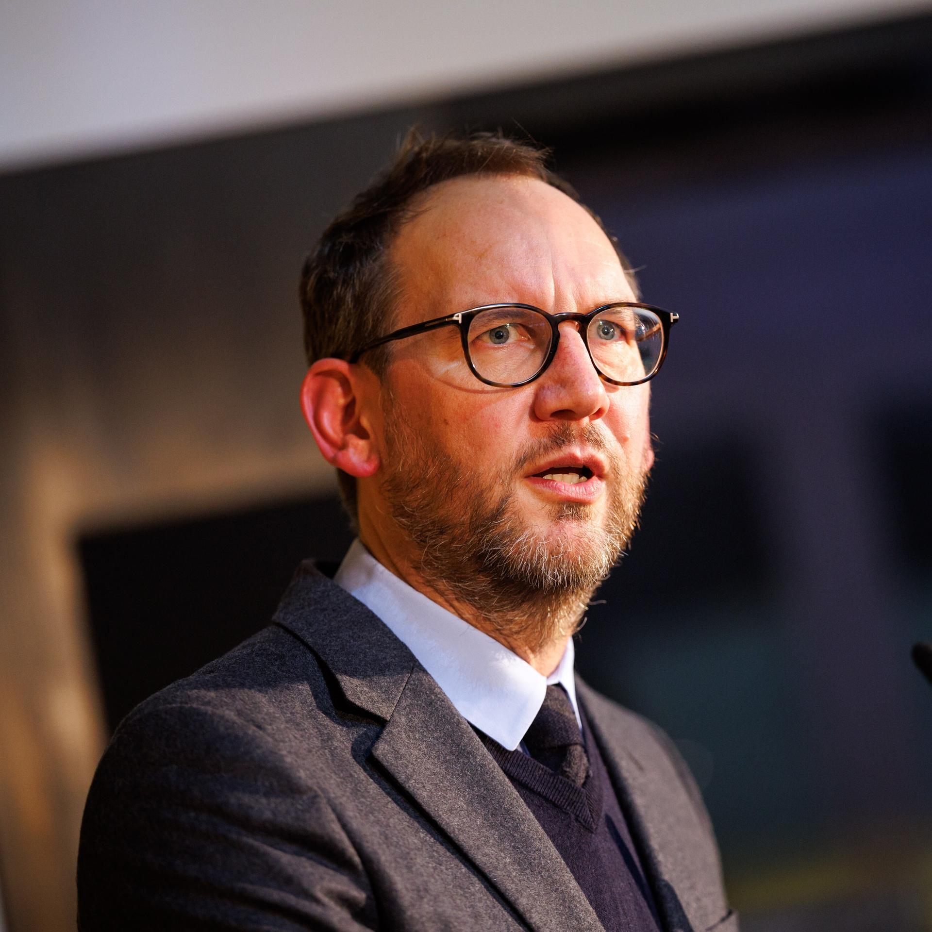 Michael Ebert, Chefredakteur des Magazins der Süddeutschen Zeitung bei einem Auftritt mit Mikrophon. Er trägt Brille und hat einen Anzug an. 