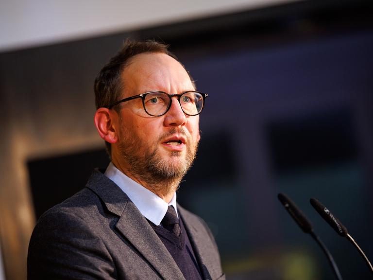 Michael Ebert, Chefredakteur des Magazins der Süddeutschen Zeitung bei einem Auftritt am Mikrophon. Er trägt Brille und hat einen Anzug an. 