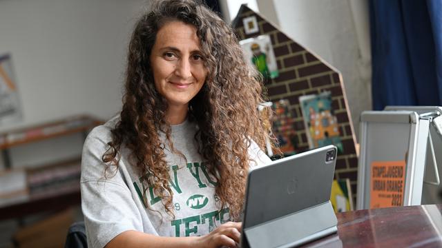 Lale Öztürk, eine Frau mit langen, lockigen Haaren, arbeitet an einem iPad. Sie koordiniert die Sprachförderung der Stadt Duisburg, macht Comedy und liest Menschen ehrenamtlich vor. Lale Öztürk, eine Frau mit langen, lockigen Haaren, arbeitet an einem iPad. Sie koordiniert die Sprachförderung der Stadt Duisburg, macht Comedy und liest Menschen ehrenamtlich vor.