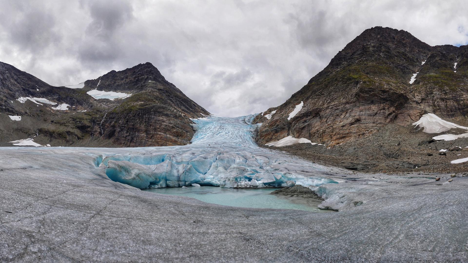 Blick auf einen Gletscher der stark geschrumpft ist sodass das darunter liegende Gebirge teilweise zu sehen ist