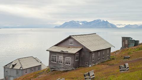 Häuser in Barentsburg, der russischen Siedlung auf Spitzbergen. Planen kaschieren den schleichenden Verfall. Im Hintergrund der Fjord und die Gletscher der Arktis.
