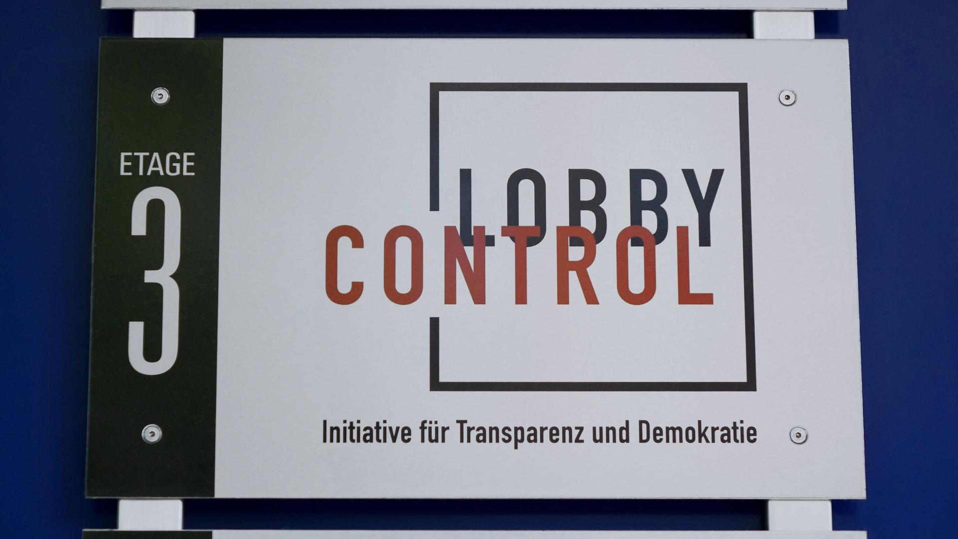 Das Logo von LobbyControl Köln, Am Justizzentrum, ist im Eingangsbereich befestigt. 