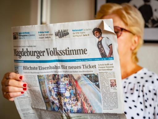 Eine Frau liest die Zeitung Magdeburger Volksstimme.