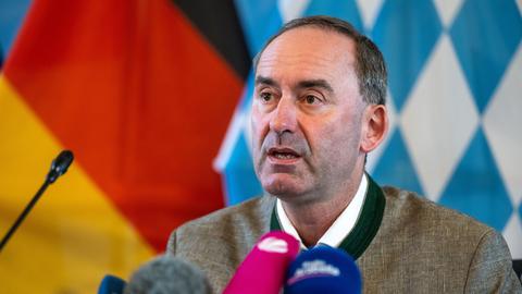 Ein Mann sitzt an einem Tisch vor lauter Mikrofonen.