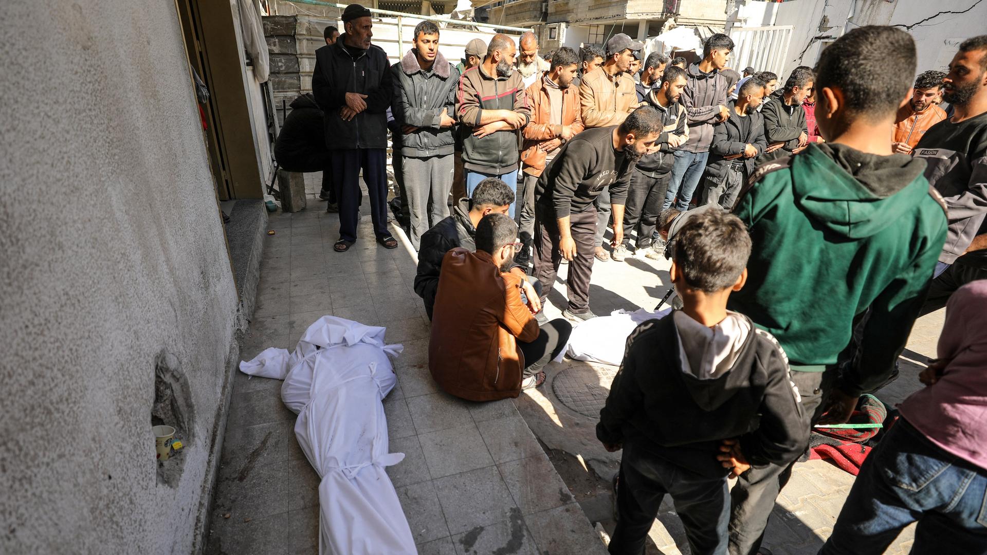 Palästinenser kümmern sich um Tote, die in weiße Leinentücher gewickelt sind.