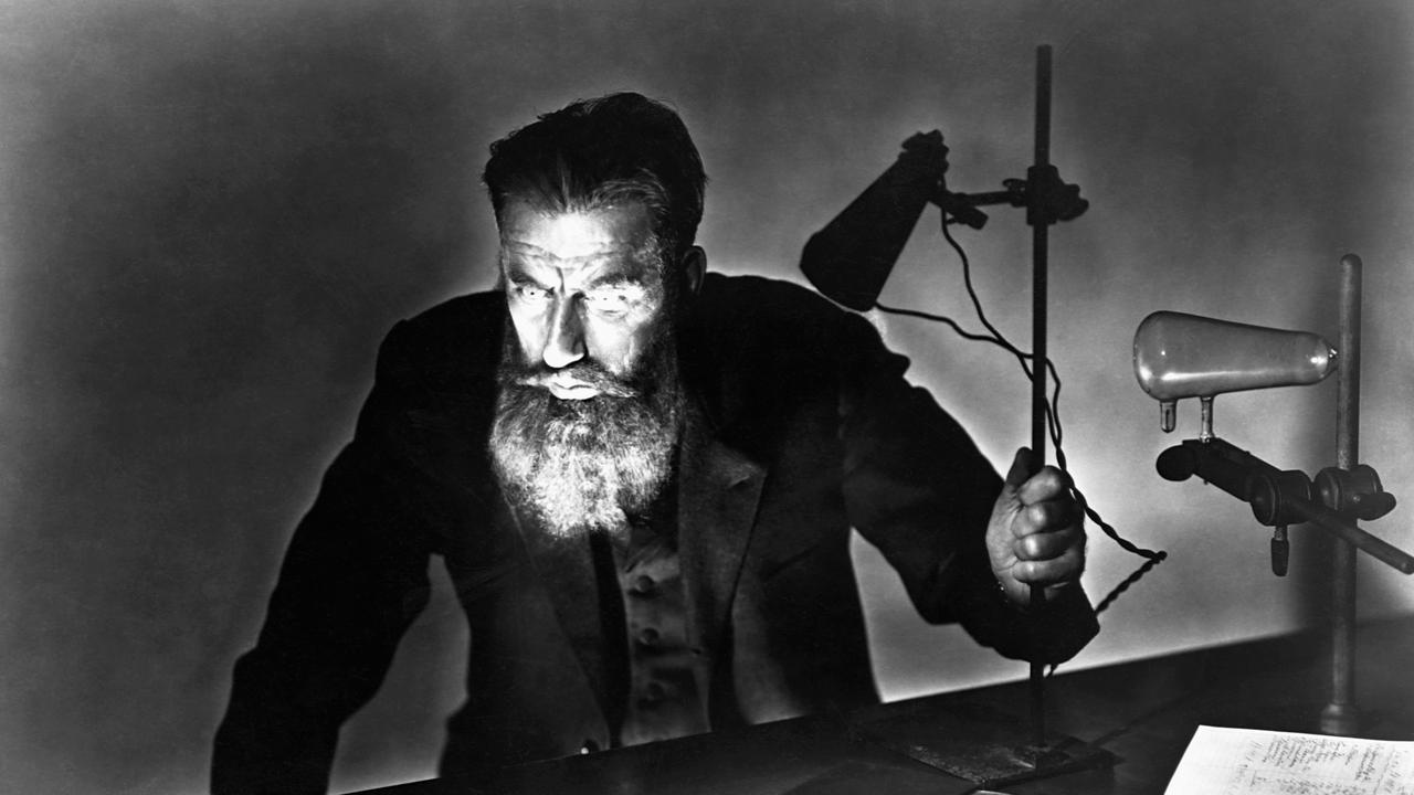 Eine undatierte historische Schwarz-Weiß-Aufnahme zeigt Wilhelm Conrad Röntgen (1845-1923), gebeugt über einen Tisch, bei dramatischem Lichteinfall einer Schreibtischlampe.   Eine undatierte historische Schwarz-Weiß-Aufnahme zeigt Wilhelm Conrad Röntgen (1845-1923), gebeugt über einen Tisch, bei dramatischem Lichteinfall einer Schreibtischlampe.